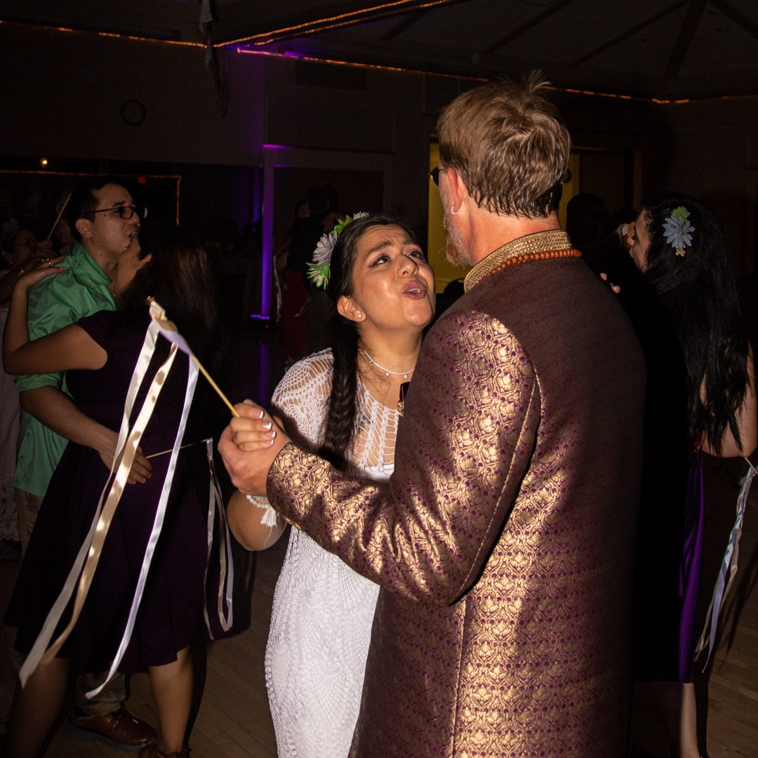 Bride singing along as she dances with the groom, ribbon wands swirling beside them