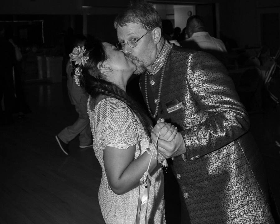 Black and white photo of newlyweds sharing a dance floor kiss
