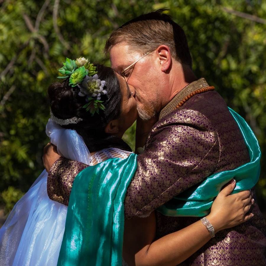 Bride and groom kissing outdoors under trees