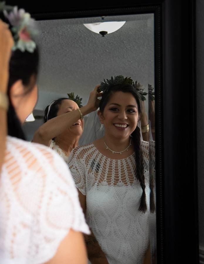 Bride having her hair and veil adjusted in a mirror