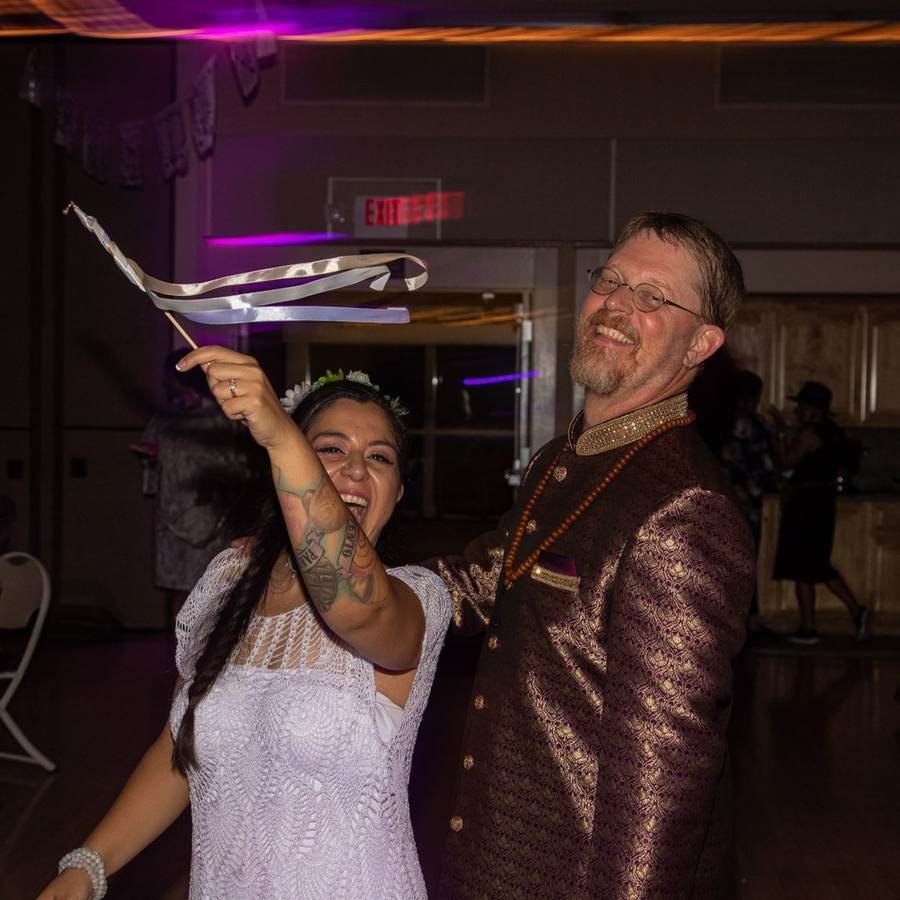 Couple laughing during a ribbon wand dance at their reception