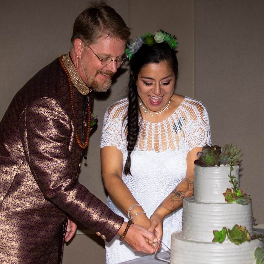 Couple cutting their wedding cake and laughing