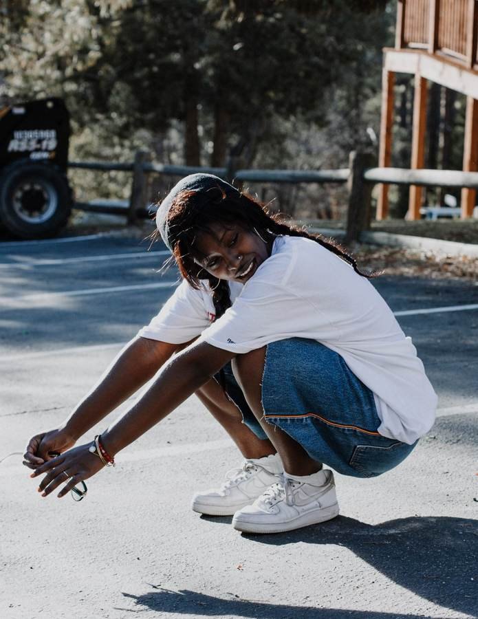 Lifestyle portrait of a young woman crouching outdoors