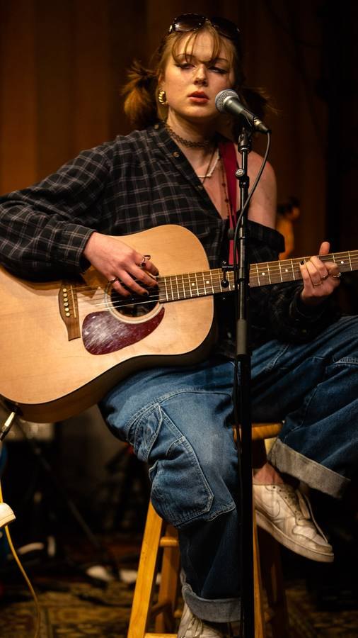 Musician playing acoustic guitar and singing at a live show
