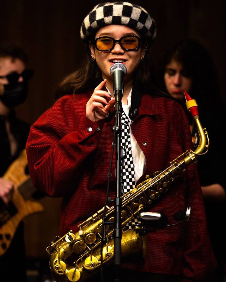 Musician with a saxophone singing into a microphone on stage