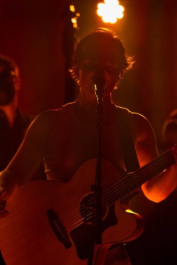 Backlit musician singing into a microphone with warm stage lighting