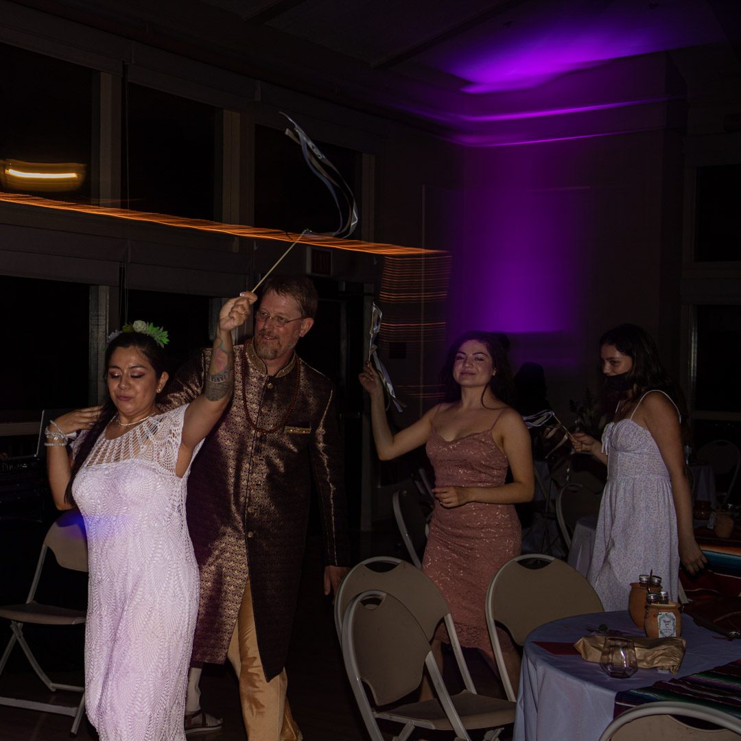 Bride and groom walking through the reception with ribbon wands